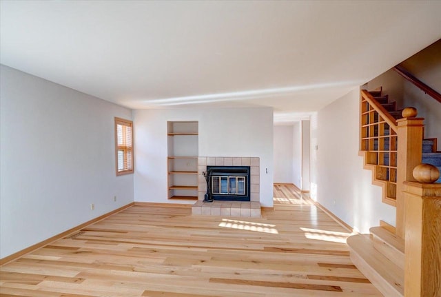 unfurnished living room featuring a tiled fireplace and light hardwood / wood-style floors