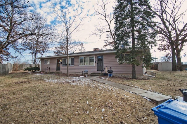 ranch-style home featuring a front lawn and a storage unit