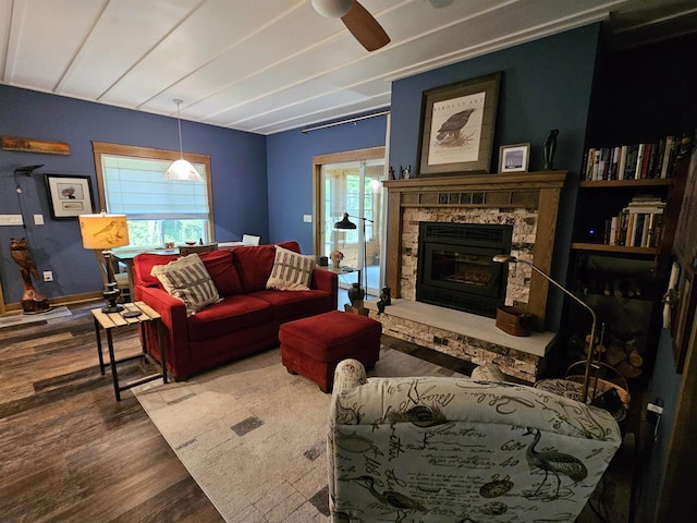 living room featuring hardwood / wood-style flooring, a stone fireplace, and ceiling fan