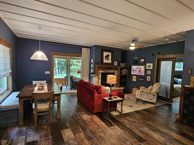 living room featuring ceiling fan, dark hardwood / wood-style flooring, and a brick fireplace