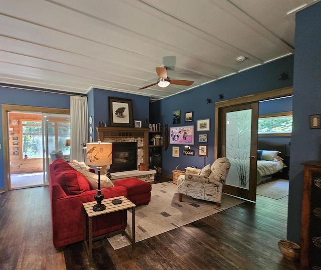 living room featuring a stone fireplace, wood-type flooring, and ceiling fan