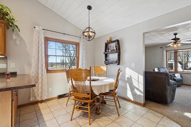 dining area with vaulted ceiling, ceiling fan with notable chandelier, and light tile patterned flooring