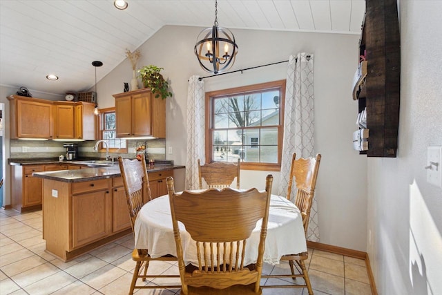 dining space with vaulted ceiling, sink, light tile patterned floors, and a chandelier