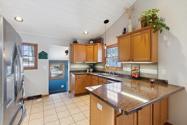 kitchen featuring decorative light fixtures, lofted ceiling, sink, kitchen peninsula, and stainless steel refrigerator with ice dispenser