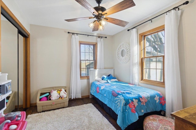 bedroom featuring dark wood-type flooring, ceiling fan, and a closet