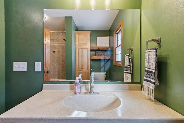 bathroom with sink, tiled shower, and toilet