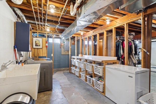 basement featuring sink, fridge, independent washer and dryer, and electric panel