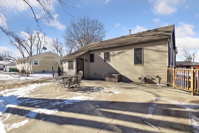 snow covered rear of property featuring a patio area