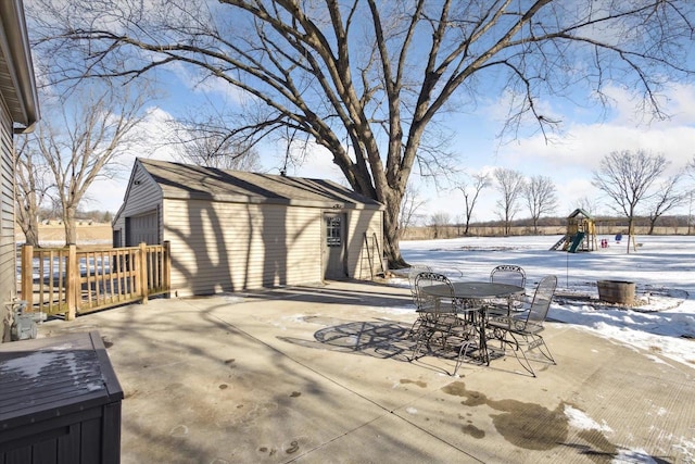 snow covered patio featuring a storage unit and a playground