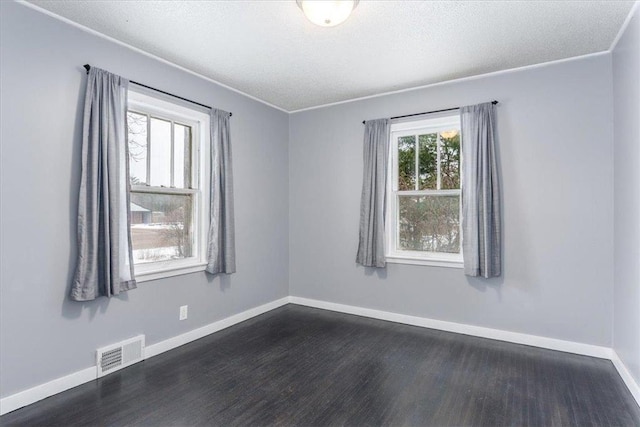 empty room featuring ornamental molding, dark hardwood / wood-style floors, and a textured ceiling