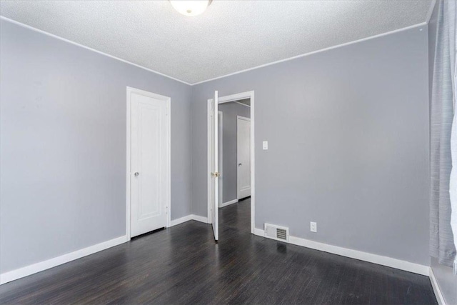 spare room featuring dark wood-type flooring and a textured ceiling