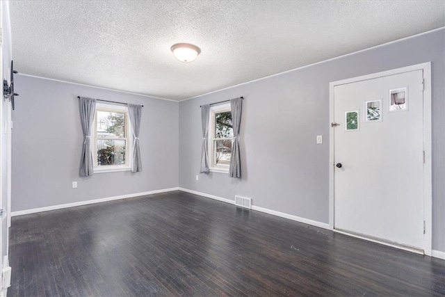 empty room with dark wood-type flooring and a textured ceiling