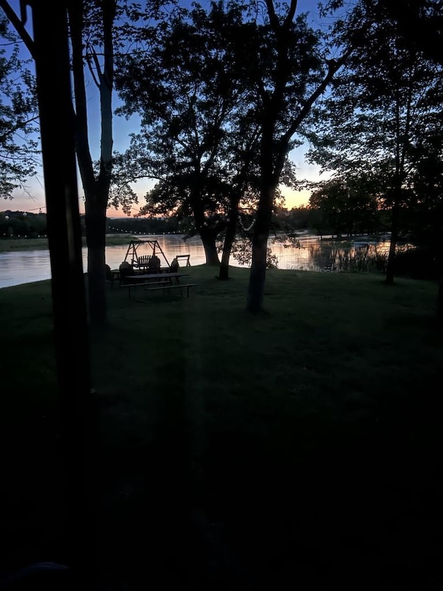 yard at dusk featuring a water view