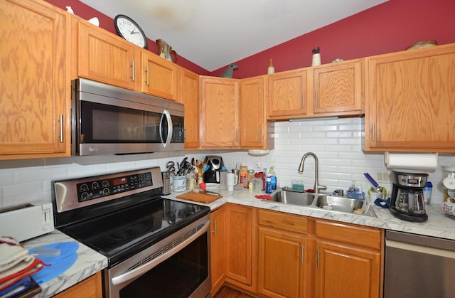 kitchen featuring stainless steel appliances, vaulted ceiling, sink, and tasteful backsplash