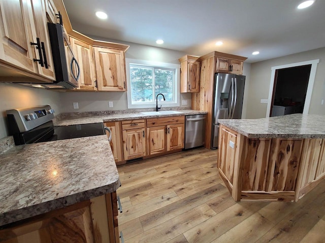 kitchen featuring a center island, appliances with stainless steel finishes, sink, and light wood-type flooring