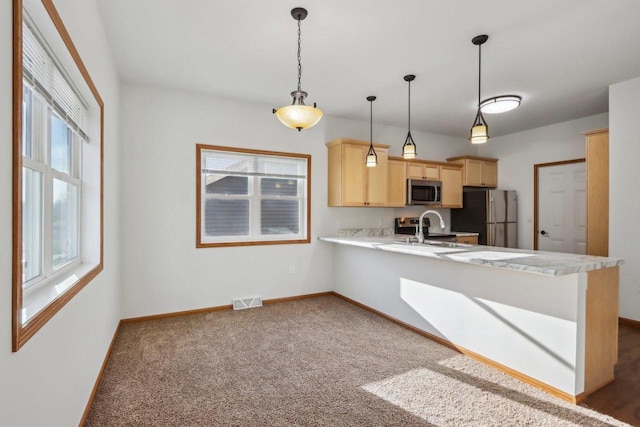 kitchen with light brown cabinetry, decorative light fixtures, sink, kitchen peninsula, and stainless steel appliances