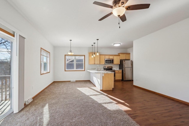 kitchen featuring decorative light fixtures, an island with sink, a kitchen bar, stainless steel appliances, and light brown cabinets