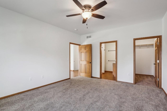 unfurnished bedroom featuring connected bathroom, a spacious closet, carpet floors, a closet, and ceiling fan