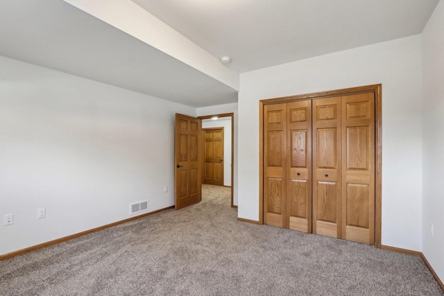 unfurnished bedroom featuring light colored carpet and a closet