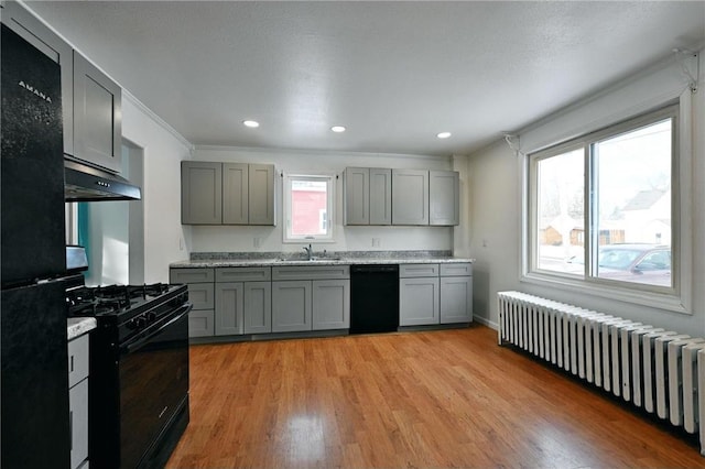 kitchen featuring sink, light hardwood / wood-style flooring, gray cabinetry, radiator heating unit, and black appliances