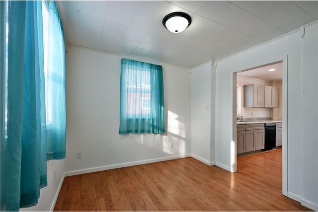 unfurnished room with crown molding, sink, and light hardwood / wood-style flooring