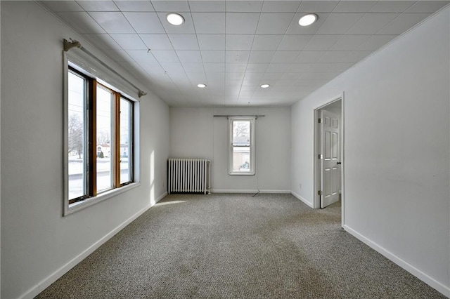 carpeted empty room featuring radiator heating unit