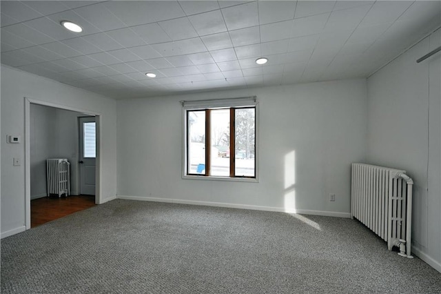 spare room featuring radiator and dark colored carpet