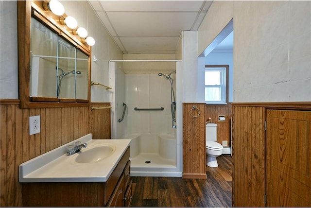 bathroom with toilet, wood walls, a shower, vanity, and hardwood / wood-style flooring