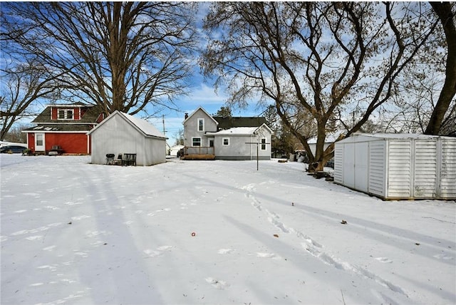 yard layered in snow featuring a wooden deck and a storage unit