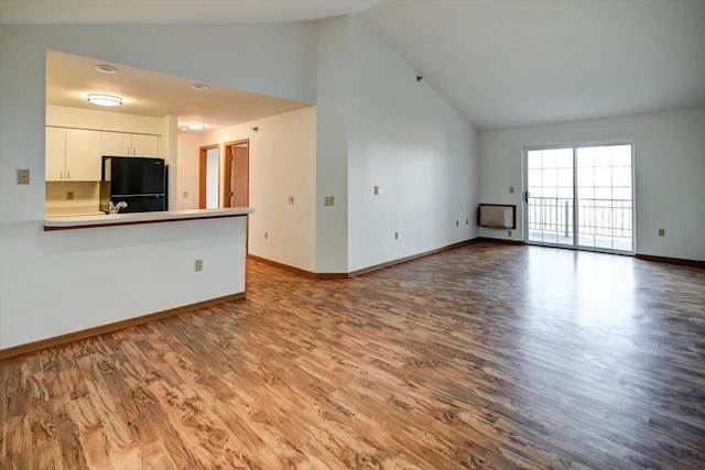 unfurnished living room with hardwood / wood-style floors and high vaulted ceiling