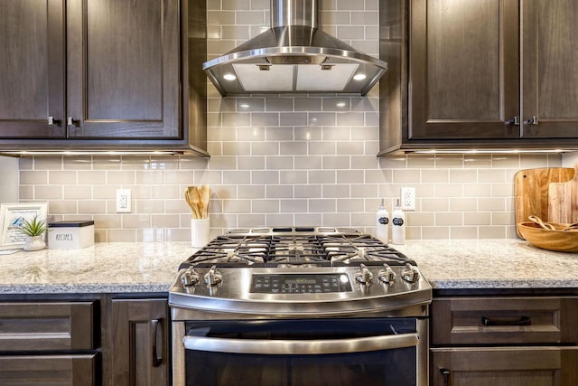 kitchen featuring ventilation hood, light stone countertops, stainless steel range with gas cooktop, and dark brown cabinetry