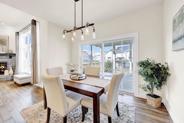 dining area with a stone fireplace and wood-type flooring