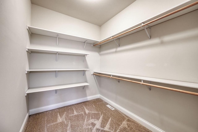 walk in closet featuring dark carpet