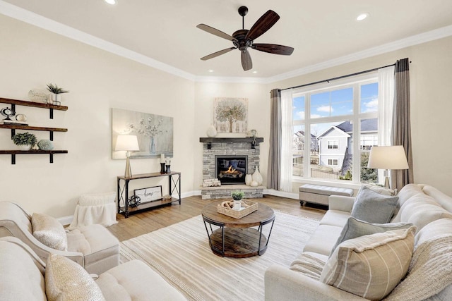 living room featuring ornamental molding, ceiling fan, a fireplace, and light hardwood / wood-style flooring