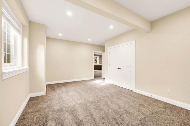 carpeted empty room with beamed ceiling