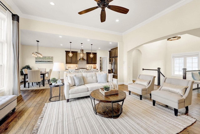 living room with crown molding, a chandelier, and light hardwood / wood-style floors