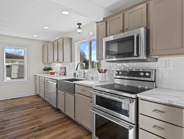 kitchen with stainless steel appliances, light stone countertops, sink, and plenty of natural light