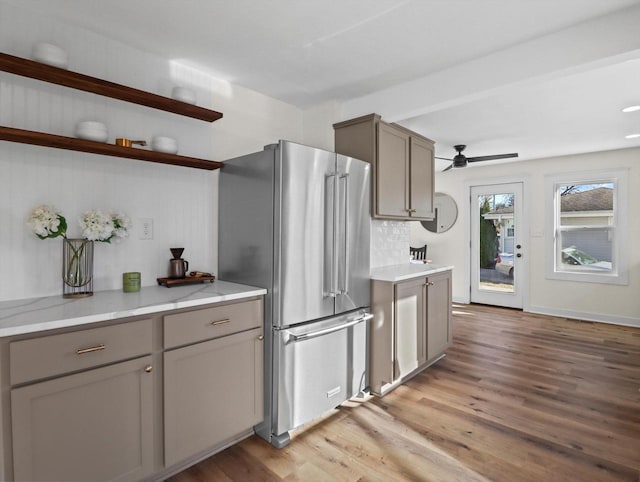 kitchen with light stone counters, light hardwood / wood-style flooring, high quality fridge, gray cabinets, and ceiling fan