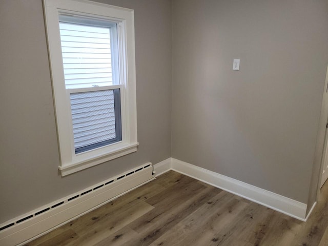 spare room with hardwood / wood-style flooring and a baseboard heating unit