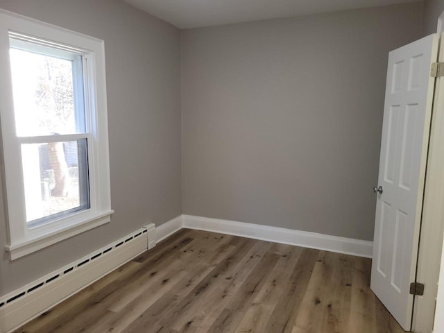 unfurnished room with a baseboard heating unit and light hardwood / wood-style flooring