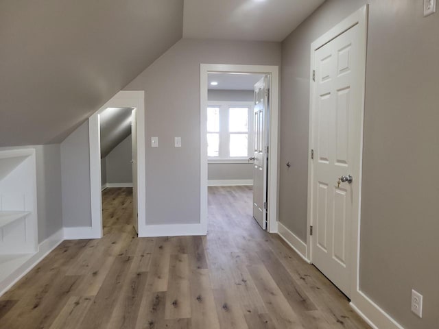 additional living space with vaulted ceiling and light wood-type flooring