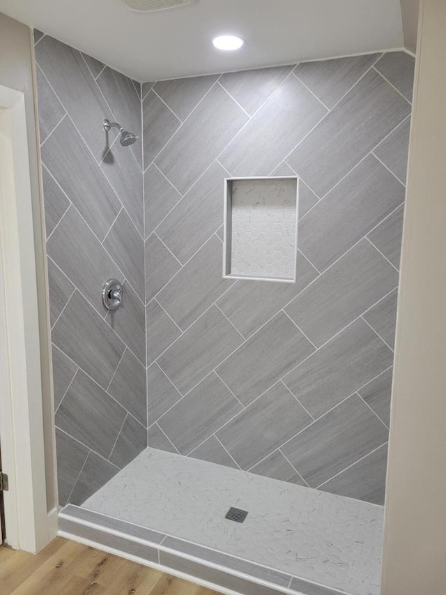 bathroom with hardwood / wood-style flooring and tiled shower