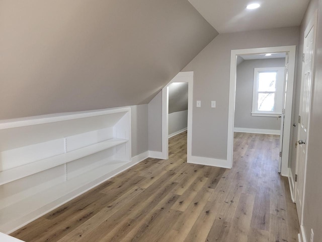 additional living space featuring vaulted ceiling and light hardwood / wood-style floors