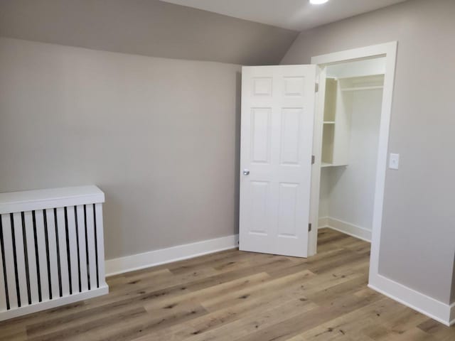 unfurnished bedroom with vaulted ceiling and light hardwood / wood-style flooring