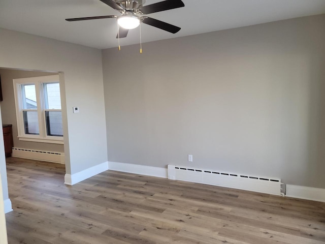 empty room featuring light hardwood / wood-style flooring, a baseboard radiator, and ceiling fan