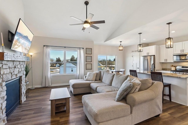 living room with dark wood-type flooring, ceiling fan, lofted ceiling, and a fireplace