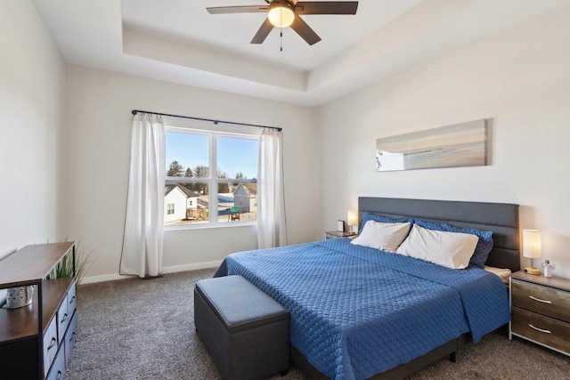 carpeted bedroom featuring a raised ceiling and ceiling fan