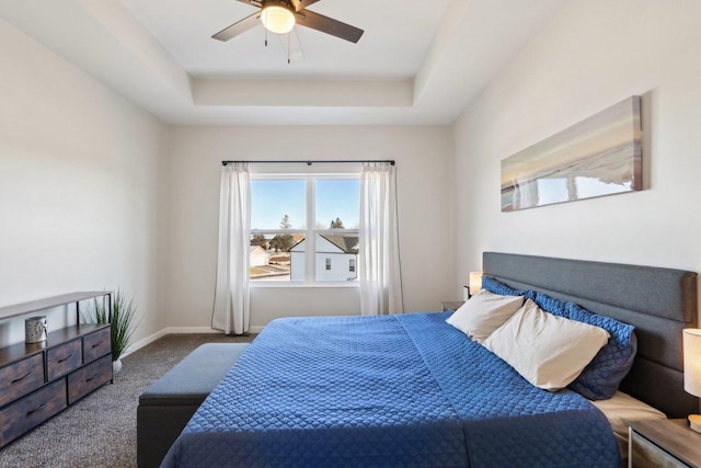 bedroom with a raised ceiling, ceiling fan, and carpet