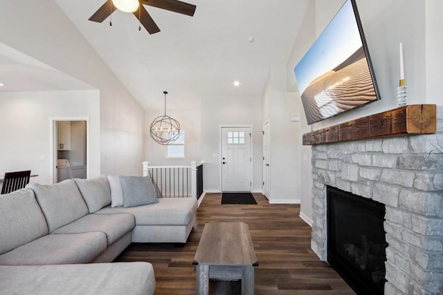 living room featuring high vaulted ceiling, washing machine and dryer, a fireplace, dark hardwood / wood-style flooring, and ceiling fan with notable chandelier