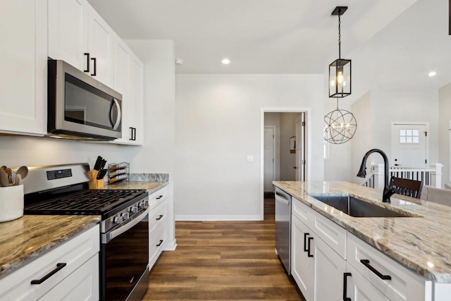 kitchen with hanging light fixtures, white cabinetry, appliances with stainless steel finishes, and sink